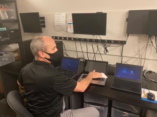 A NetEffect technician setting up laptops at the workbench