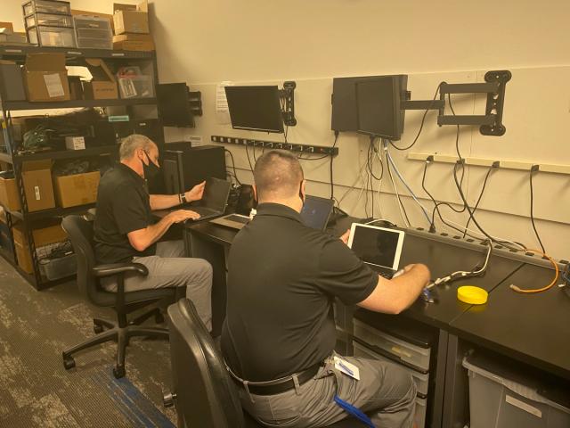 Two NetEffect technicians configuring monitors and network equipment