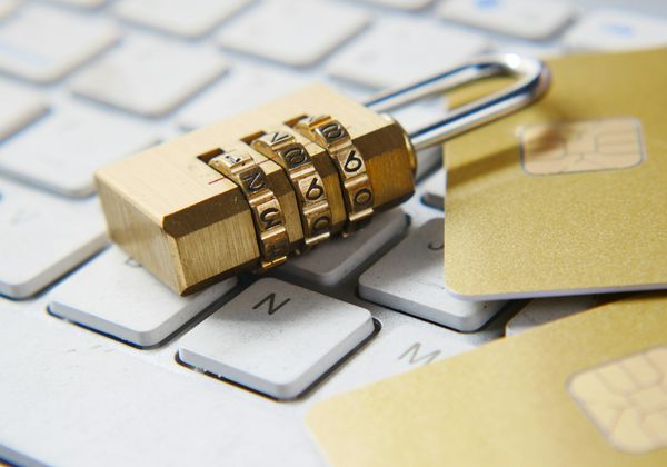 A padlock resting on a keyboard beside chip payment cards